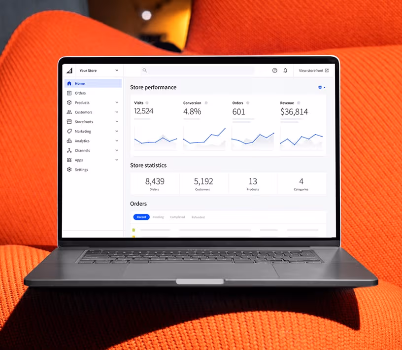 A laptop displaying an e-commerce store performance dashboard on an orange surface.