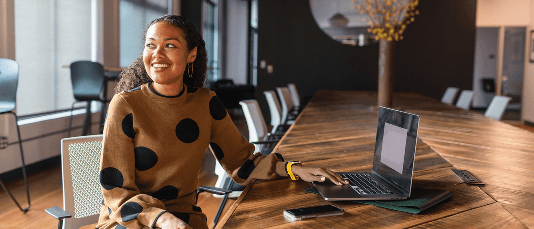 Mujer sonriente sentada en una mesa de conferencias vacía
